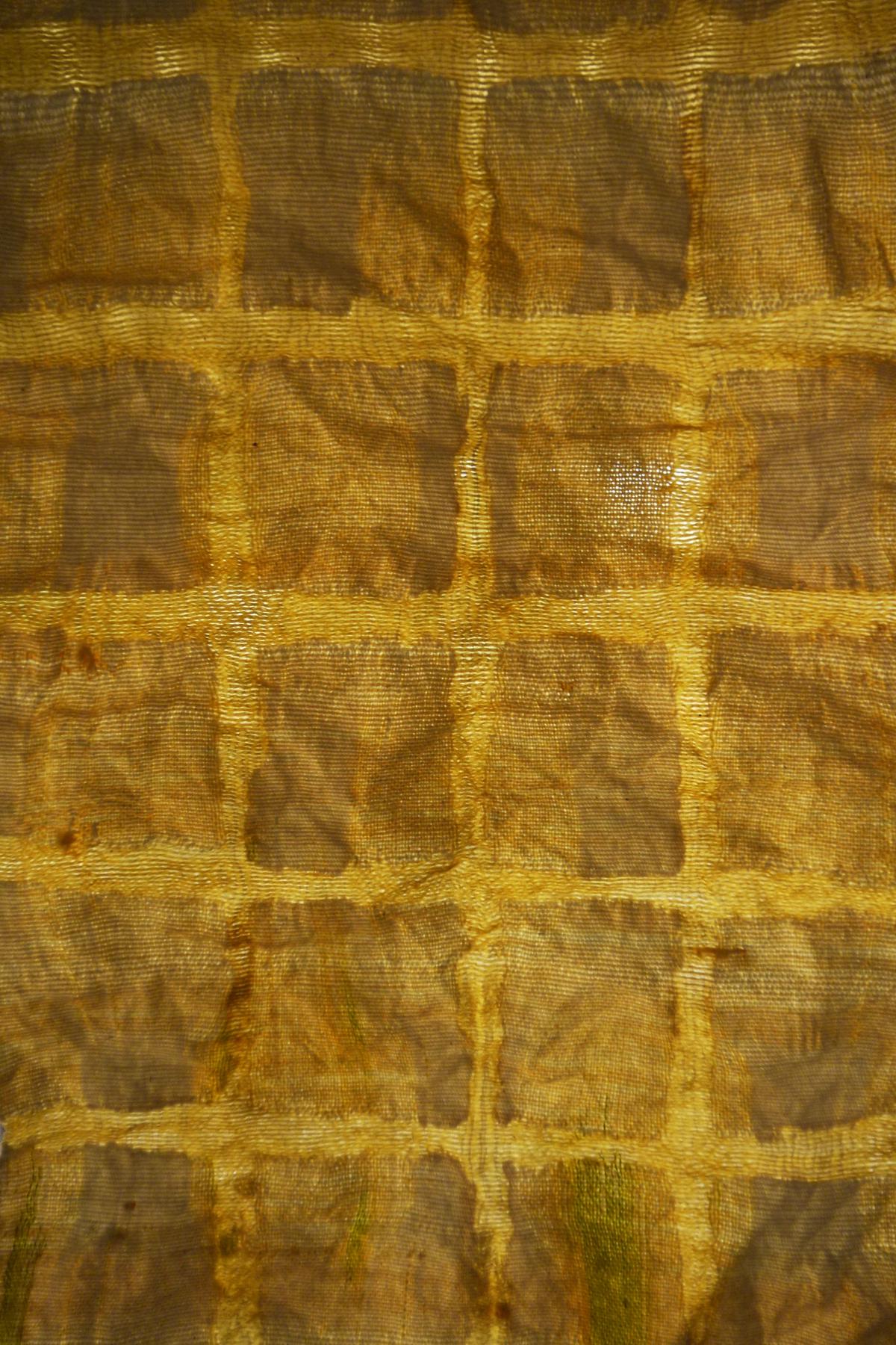 a yellow cloth letting sunlight through, where a grid of warp has been burned away