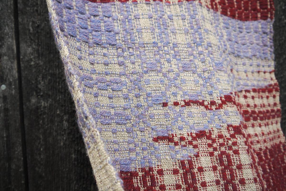 close-up of pale blue wool making irregular waves into an area of rich red
